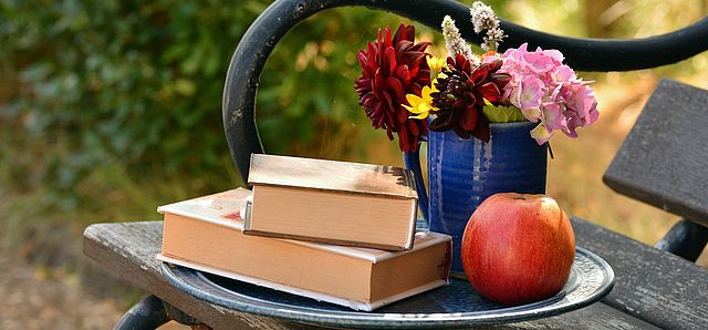 Gartenidyll, zwei Bücher, ein Apfel und Blumen