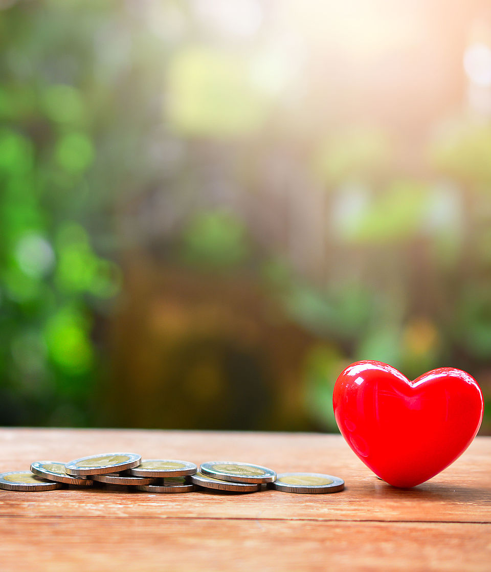 Spendendose, Geld liegt daneben und ein rotes Herz