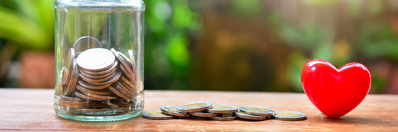 Spendendose, Geld liegt daneben und ein rotes Herz