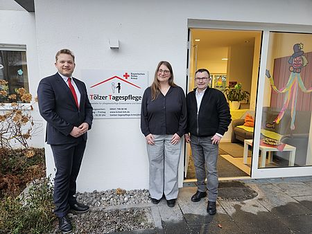 Herr Eichenseher, Herr Schäfer und Frau Gipfel stehen vor dem Eingang der neuen Tölzer Tagespflege des Bayerischen Roten Kreuzes